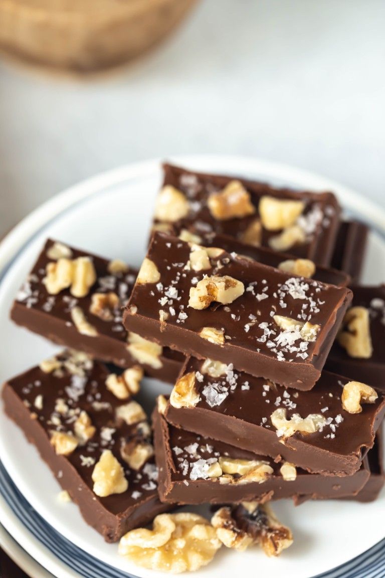 stack of vegan fudge pieces with walnuts and flaked sea salt on plate