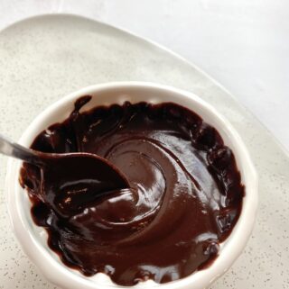 spoon swirling in white bowl of vegan nutella