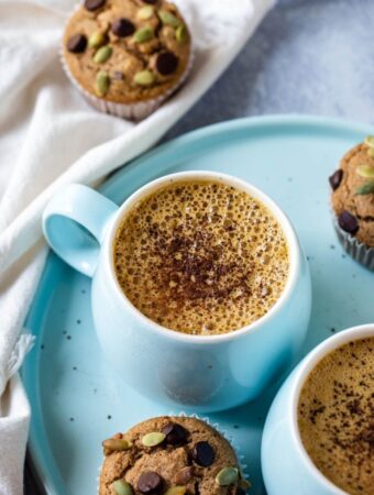 closeup of vegan pumpkin spice latte with cinnamon sprinkles in blue mug