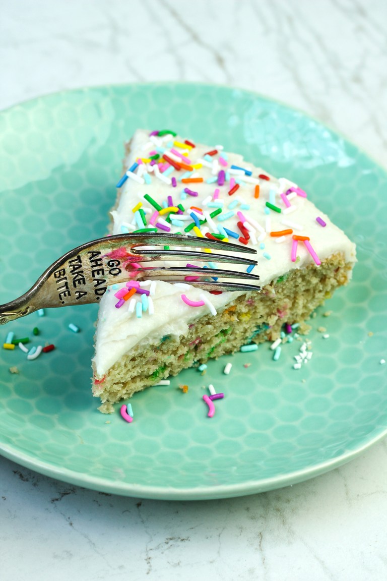 Fork slicing into vegan funfetti cake with vanilla buttercream
