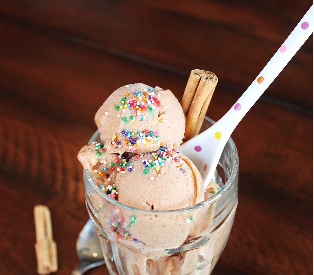 2 scoops of vegan cinnamon ice cream in glass cup with spoon