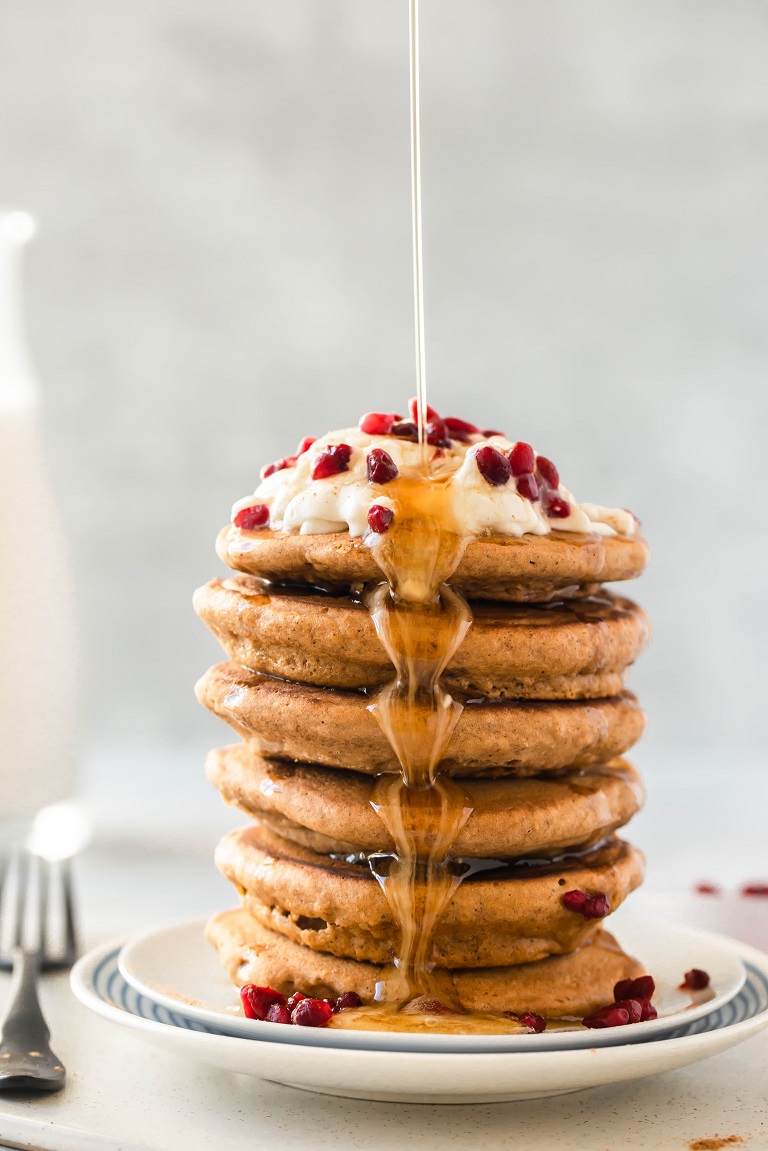 syrup pouring over stack of pancakes on white plate