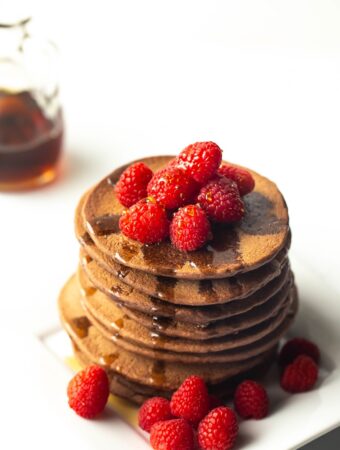 stack of vegan chocolate protein pancakes with raspberries on top