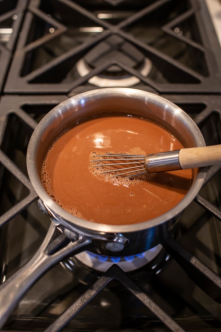 pot over stove heating up peppermint mocha latte with whisk